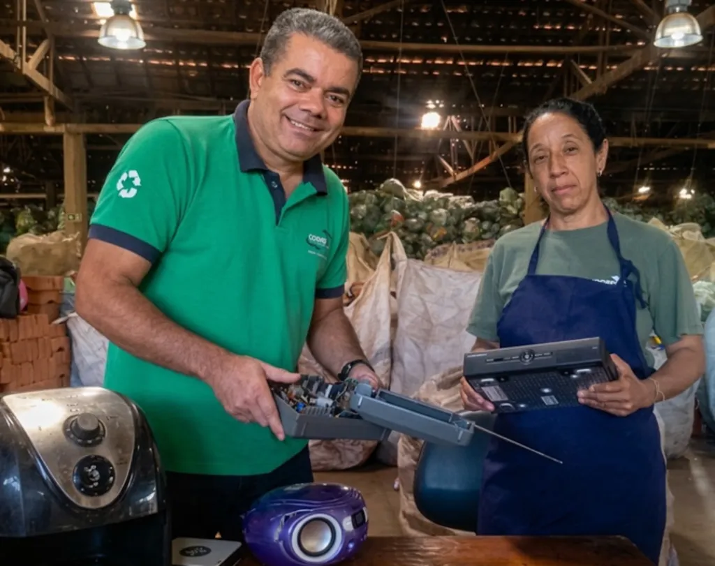 homem de camisa verde e mulher de jaleco azul manipulam equipamentos eletônicos sobr uma bancada