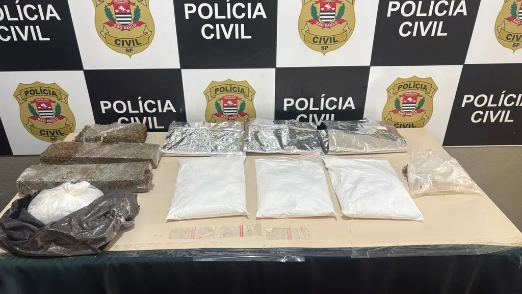 grande quantidade de drogas sobre mesa com brasão policial ao fundo