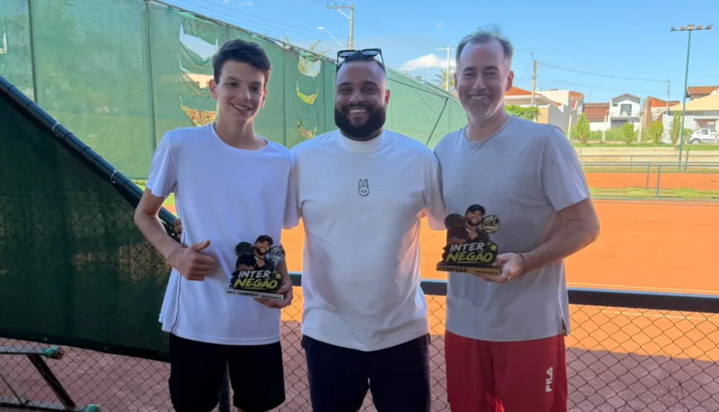 TRÊS HOMENS seguram troféus e sorriem para a câmera vestindo roupas esportivas