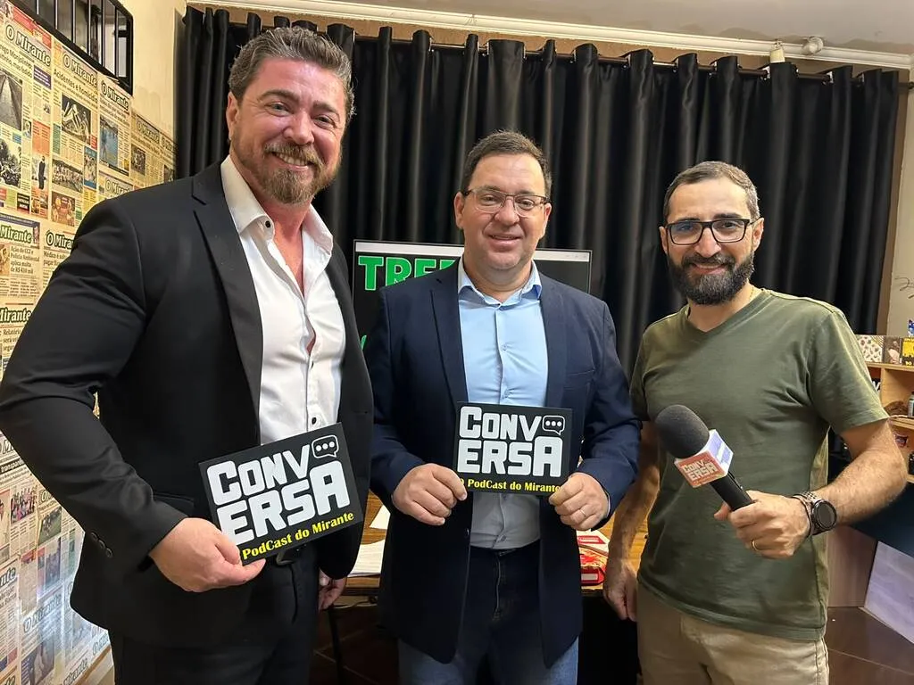 três homens posam para foto seguranda placas escrito conversa, em estúdio com luzes e microfones