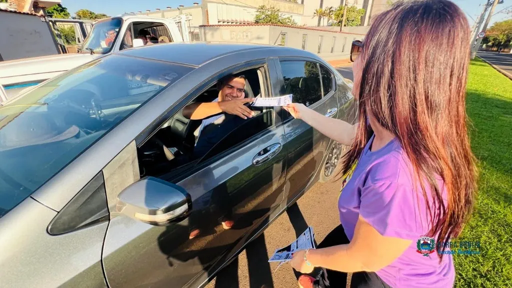 Agentes e voluntários distribuem panfletos da campanha Agosto Lilás em vias de grande movimento em Barra Bonita