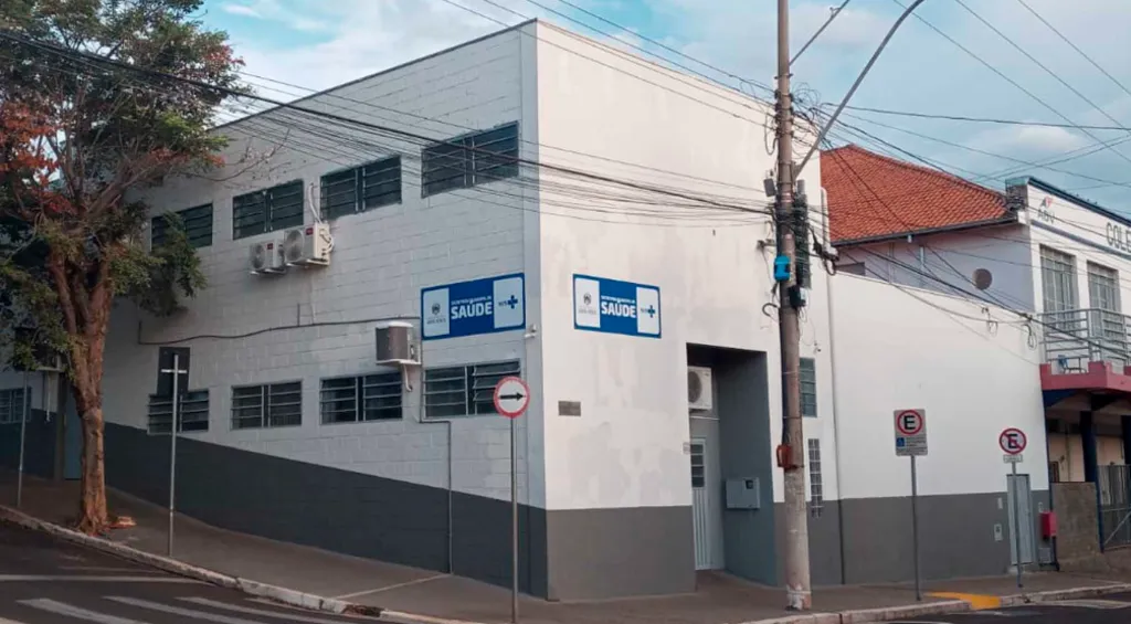 prédio branco de esquina, em áisagem urbana carregada, com placas com dizeres saúde na fachada