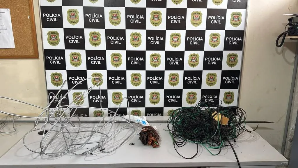 Fios de cobre retorcidos em cima de uma mesa, com painel da Polícia Civil ao fundo